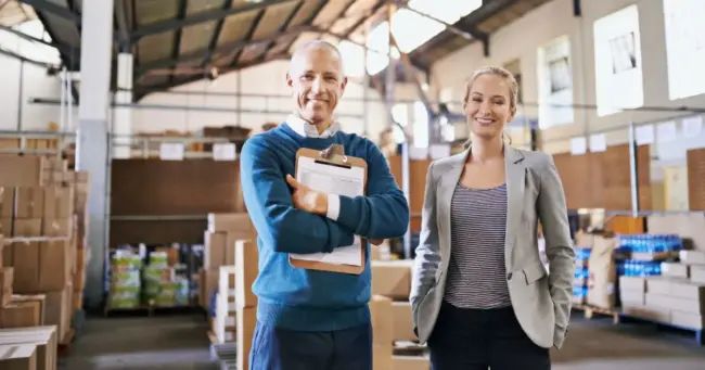 Logistics manager and colleague smiling in a Salt Lake City, Utah warehouse