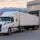 White semi-truck trailer parked at warehouse loading dock with forklift loading pallets in Salt Lake City