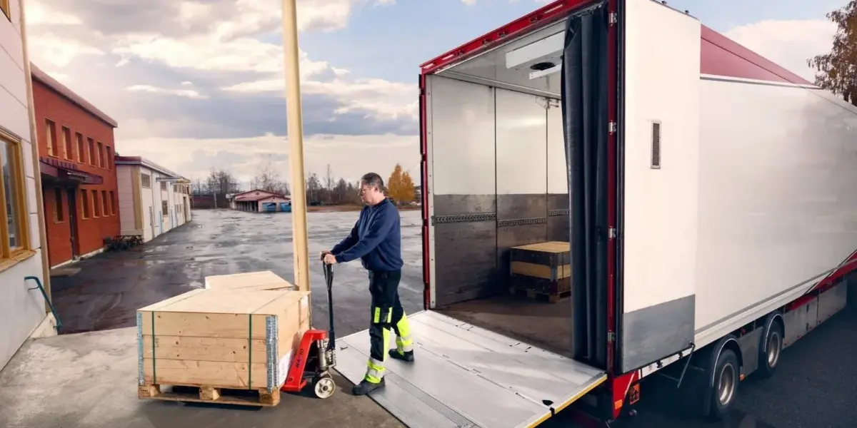 Freight truck with a lowered lift gate and palletized cargo at a delivery location